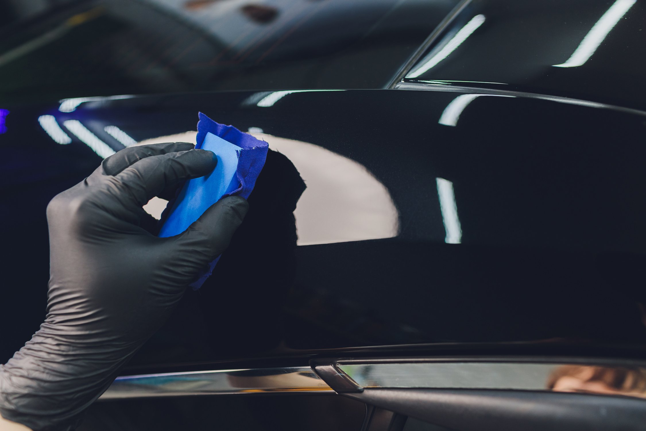 Car detailing - Man applies nano protective coating to the car. Selective focus.